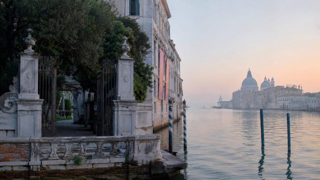 Venise à l’aube, façades classiques, lagune calme et entrée de jardin d’exposition évoquant la Biennale 2026, la beauté et la mémoire artistique.